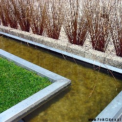 Strak vormegeven waterloop door tuinotwerp van bron naar vijver, met beplantingsrand Carex buchiana Red Tails